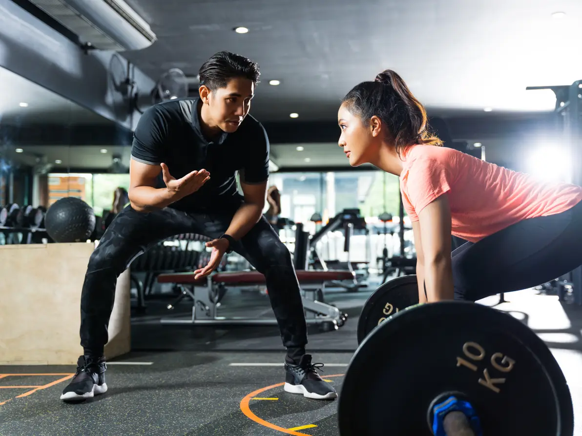 A trainer coaching a strength exercise.