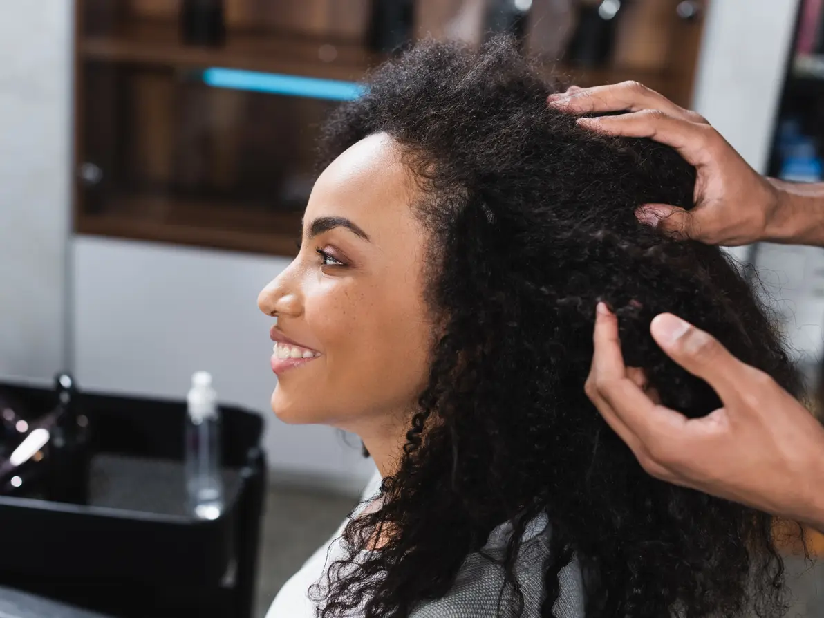 A hairdresser styling a client's curly hair in a salon.