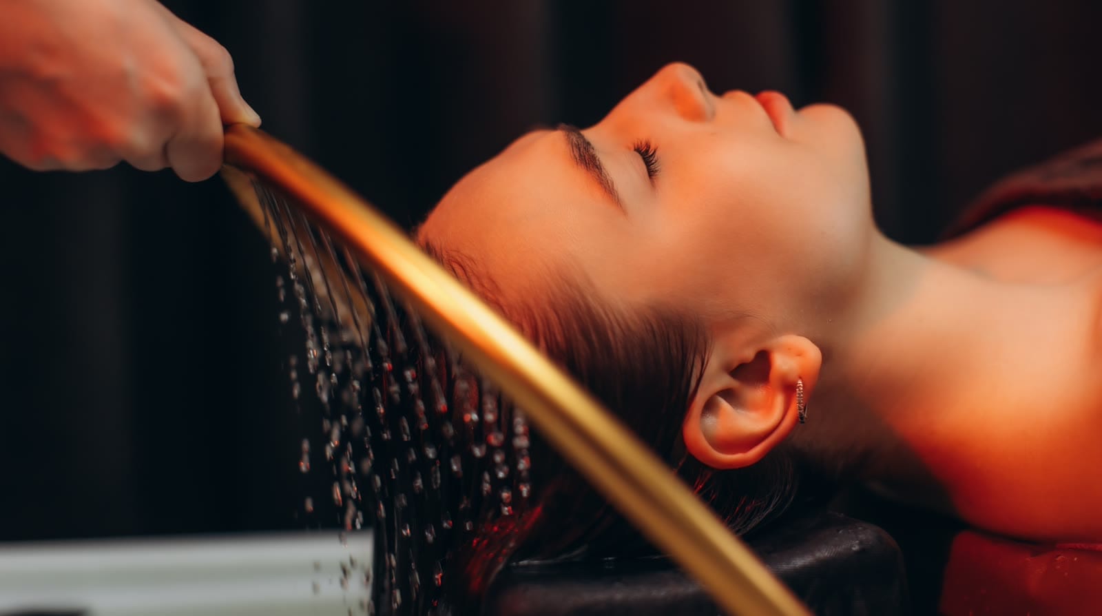 A guest lying back as warm water arcs over her scalp during a headspa ritual